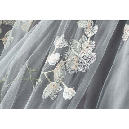 Close-up of delicate embroidered floral design on soft gray tulle fabric, ideal for summer midi skirts.