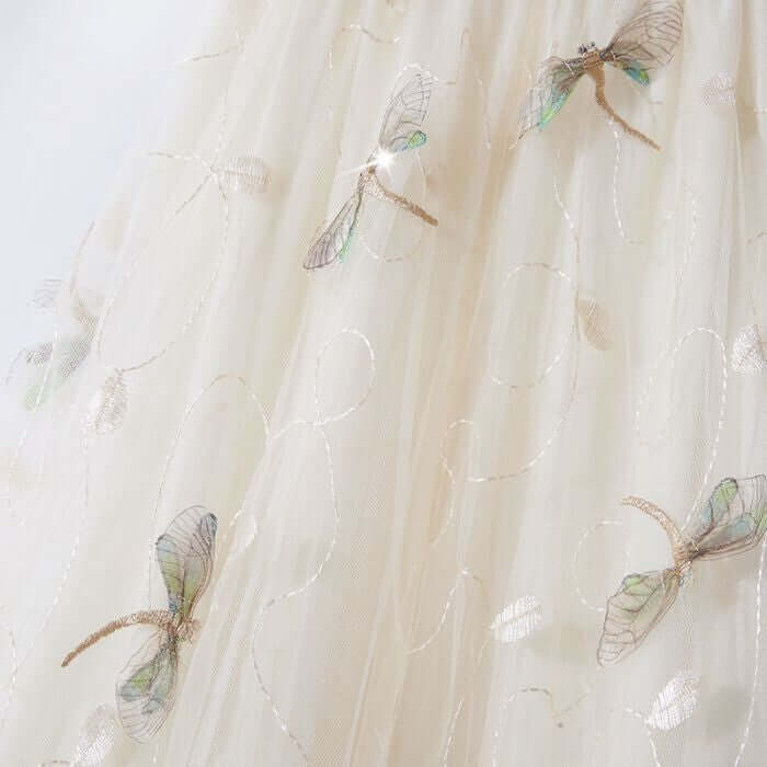 Elegant embroidered cream tulle fabric featuring delicate dragonfly designs, perfect for a chic midi skirt.