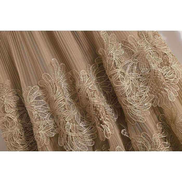 Close-up of elegant lace detailing on a beige tulle skirt, showcasing intricate floral patterns for a sophisticated look.