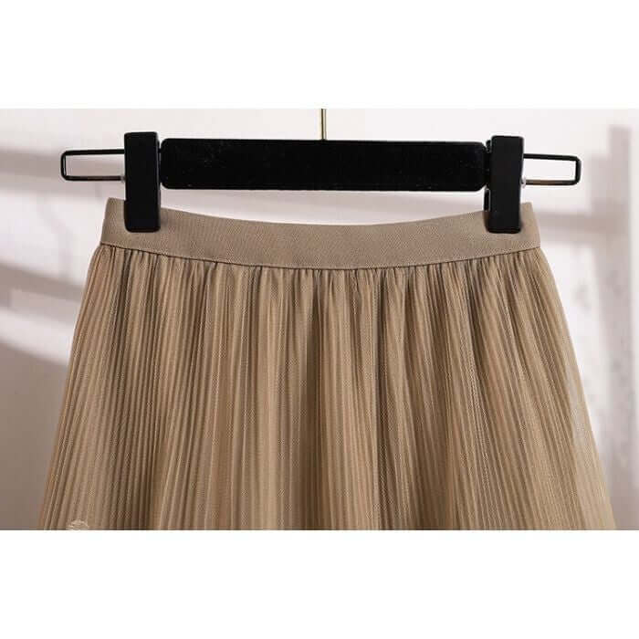 Close-up of the waistband of a beige pleated midi skirt showcasing stylish texture and design.