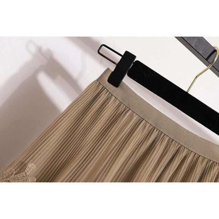 Close-up of the waistband and pleats of a beige lace and tulle midi skirt on a hanger, showcasing its elegant design.
